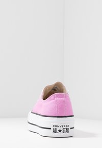 Baskets en toile rose à profil bas, semelle en caoutchouc blanche et accents noirs. Présentent le logo "Converse All Star" sur le talon.