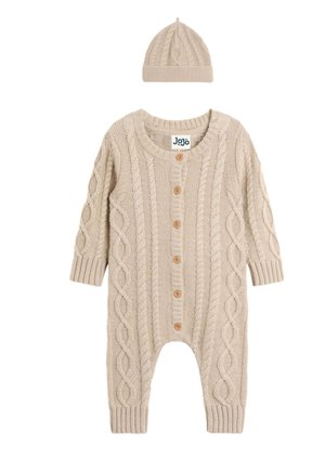 Bež pleteni dječji kombinezon s uzorkom pletenica i drvenim gumbima, u paru s odgovarajućom pletenom kapicom.