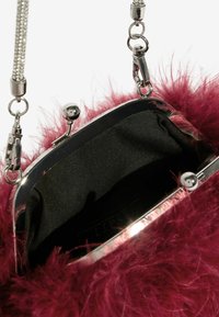 Dirbtinės odos rankinė sodriame magento atspalvyje su sidabriniu metaliniu rėmu. Vidus išklotas juodu audiniu. Grandinėlės dirželis su metaliniais akcentais.