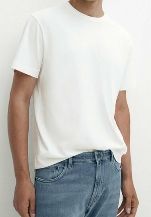 Weißes kurzärmeliges T-Shirt aus weichem Stoff, kombiniert mit hellblauen Jeans. Einfaches Design mit Rundhalsausschnitt und ohne sichtbare Logos.