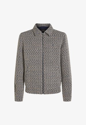 Kootud jakk tekstuurilise kootud kangaga tumesinisel ja beezil. Omab kraed ja pikki varrukaid, kerge läike ja struktureeritud lõige.