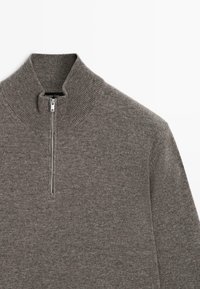 Maglione grigio a coste con mezza zip e colletto alto, che mostra la parte superiore anteriore su uno sfondo bianco.