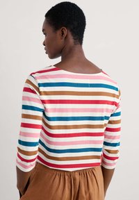 Gestreiftes, tailliertes Oberteil mit Dreiviertelärmeln. Die Farben umfassen Rot, Pink, Blau, Braun und Weiß. Aus weichem Stoff und mit rundem Ausschnitt.