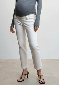 Jeans blancos de pierna recta hechos de denim con una textura suave, combinados con una camiseta gris de manga larga y sandalias negras de tiras.