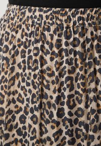 Sukně s leopardím vzorem, která má Řasenou texturu, elastický pas a je v odstínech béžové, černé a hnědé.