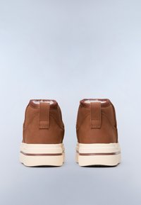 Zapatos de piel marrón de caña alta con una textura suave, suela de goma crema y un lazo trasero para facilitar el calzado. Sin patrones ni acentos visibles.