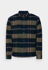 Koszula flanelowa w granatowo-zieloną kratę z beżowymi paskami. Posiada dwie kieszenie na piersi i zapięcie na guziki z przodu. Miękka w dotyku.