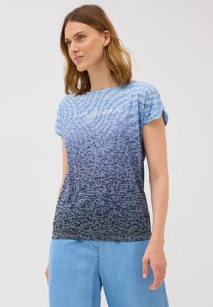 T-shirt en dégradé de bleu, fabriqué en tissu doux, avec un motif texturé et le texte "NATURE SANS FIN" en blanc sur le devant.