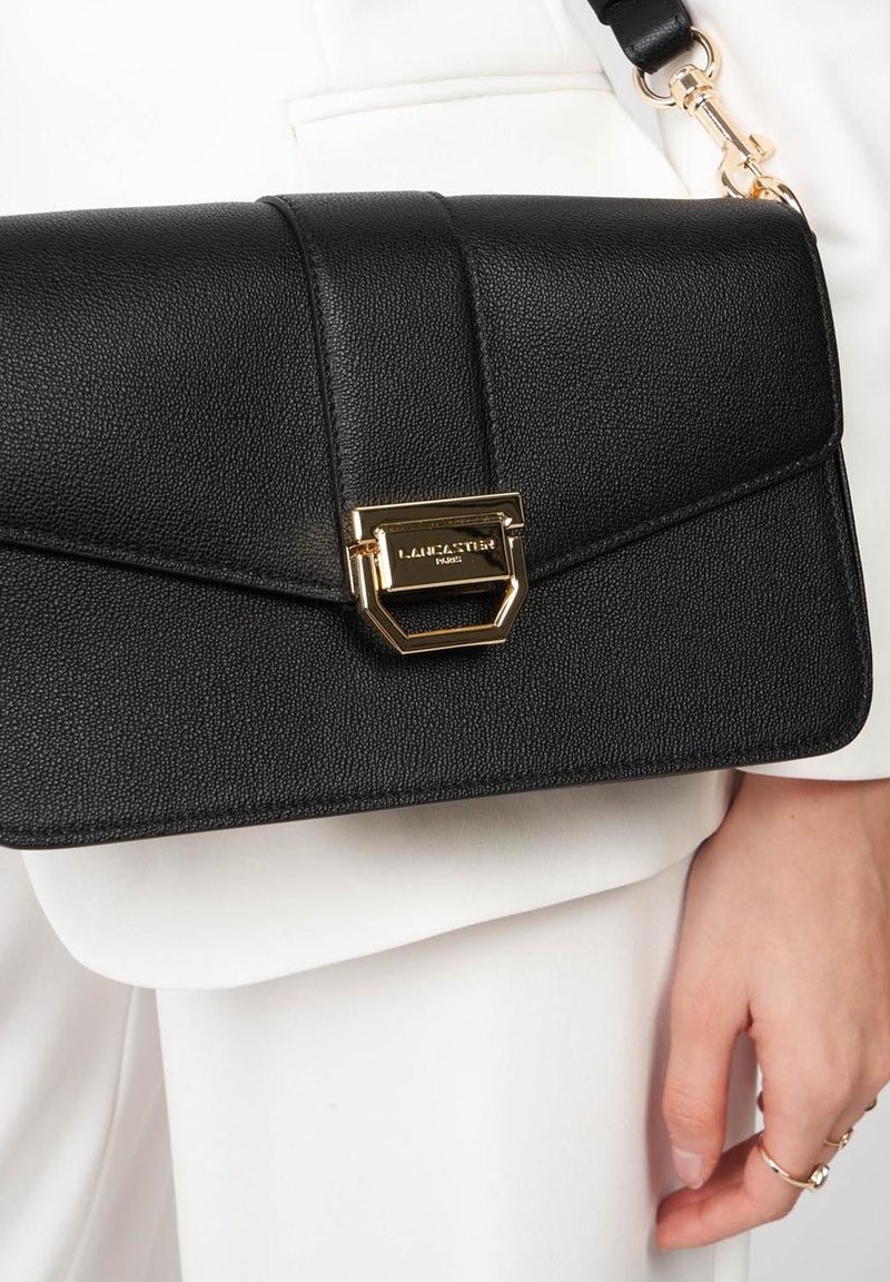 Borse a mano in pelle nera con finitura testurizzata, chiusura in hardware dorato e tracolla removibile. Presenta un design geometrico sulla pattina.