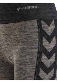 Czarne i szare legginsy Hummel z teksturowanym wzorem, z akcentem w kształcie chevronu wzdłuż boku i dopasowaną, wysoką talią.