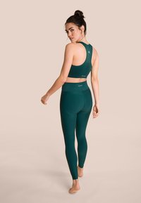 Teal sportoutfit bestaande uit een aansluitende sportbeha en bijpassende high-waisted leggings, ontworpen met een gladde stof en een naadloze uitstraling.