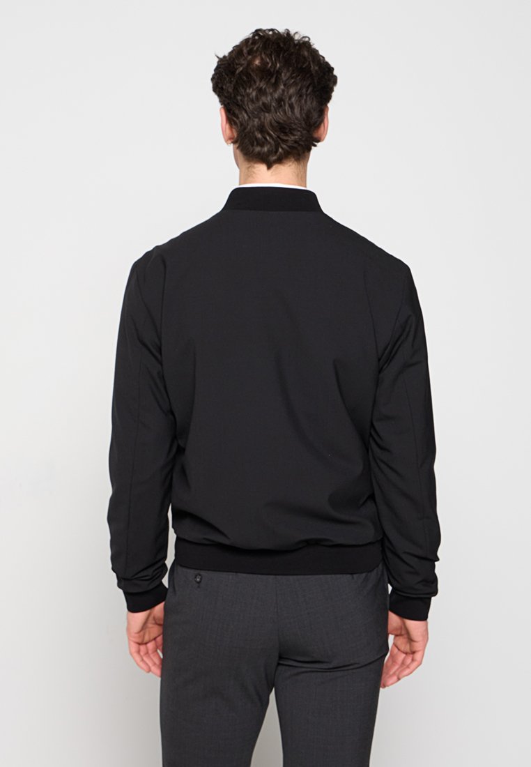 Schwarze Bomberjacke mit glatter Textur, gerippten Bündchen und Saum, Stehkragen und minimalistischer Gestaltung. Maßgeschneiderte Passform.