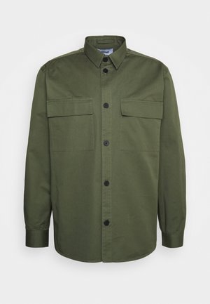 Oliwkowa koszula wykonana z bawełny. Posiada kołnierz typu spread, zapięcie na guziki i dwie kieszenie na piersi. Gładka tekstura z prostym krojem.