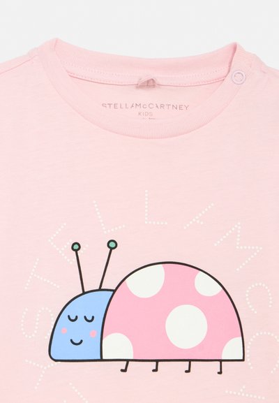 Pink børneskjorte med en smilende blå og pink tegneserie mariehøne med hvide pletter og teksten "STELLA MCCARTNEY" over designet.