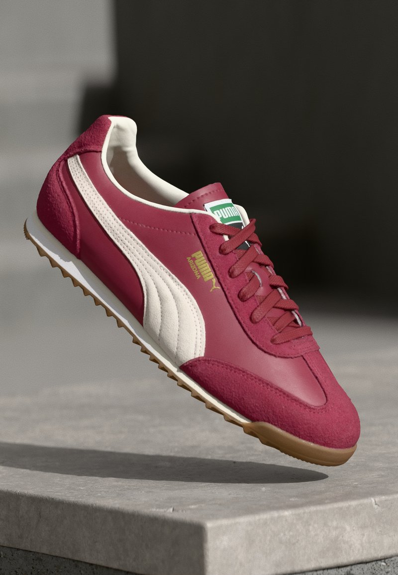 Puma superge v burgundski usnjeni barvi z belimi detajli. Vključujejo zlat logotip, strukturiran sueden panel in strukturirano gumijasto podplat za oprijem.