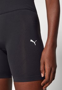 Černé sportovní šortky vyrobené z elastické tkaniny s texturovanými panely, s bílým logem Puma na boku a přiléhavým střihem.