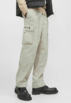 Beige cargobroek met meerdere zijzakken, gemaakt van lichte stof. Beschikt over een logo patch en taps toelopende enkels. Te combineren met zwarte laarzen.