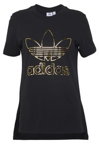 Svart bomullströja med en glänsande guld Adidas-logotyp och trefoil-design framtill. Kortsleeves med sidofickor vid nederkanten.