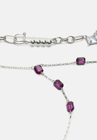 Strieborný reťazový náhrdelník s obdĺžnikovými fialovými drahokamami a druhou reťazou so striebornými korálkami a štvorcovým priezračným zapínaním.