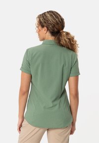 Green checkered short-sleeve shirt with a collar, featuring a lightweight fabric and a curved hemline, visible from the back.