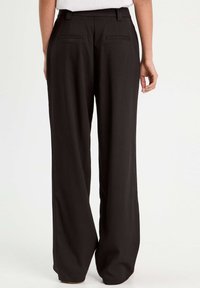 Pantaloni neri a gamba larga con una finitura in tessuto liscia, dotati di una vita, passanti per cintura e due tasche posteriori.