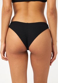 Czarne majtki bikini z teksturowanym wzorem, wysokim krojem nóg i niskim stanem, prezentujące gładkie wykończenie i minimalne zakrycie.