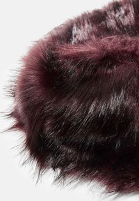 Bordeaux faux pelsstof med lange, bløde fibre. Teksturen ser fluffy ud med en blank glans, der viser ujævne længder og lag.