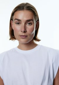 Witte katoenen t-shirt met korte mouwen, een ronde halslijn en een gladde textuur. Eenvoudig ontwerp zonder zichtbare patronen of versieringen.