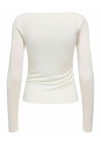 Garām piedurknēm tops no mīksta, elastīga auduma krēmkrāsā. Aprīkots ar laivas tipa kakla izgriezumu un sānu rievotām detaļām papildus tekstūras radīšanai.