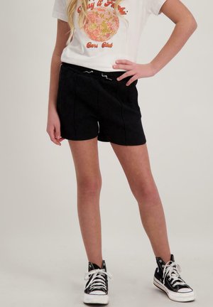 Zwarte shorts met een zachte textuur en een elastische tailleband, gecombineerd met een wit graphic t-shirt en zwarte high-top sneakers.