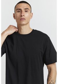 Black crew-neck t-shirt made of soft fabric, featuring short sleeves and a relaxed fit. Simple design with clean lines and no patterns.