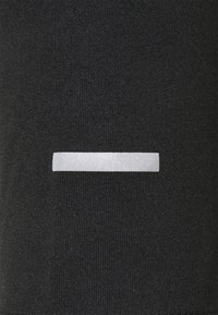 Svart textilmaterial med en slät, glänsande silverrand över mitten, vilket skapar en kontrast i textur och färg.