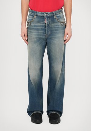 Vaqueros azul claro de pierna ancha hechos de mezclilla, con áreas descoloridas y abalorios decorativos en los bolsillos delanteros. Combinados con zapatos negros.