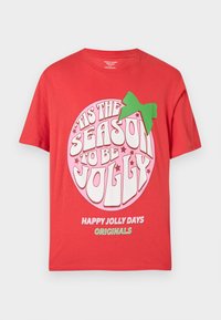 Tricou din bumbac roșu cu un grafic circular mare roz, având text alb și verde care citește "Este sezonul să fim veseli" și un accent cu fundiță verde.