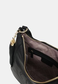 Zwarte leren handtas met een gouden rits en metalen onderdelen, voorzien van een lichtroze interieur met logo-patroon en een ritsvak.