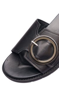 Sandale en cuir noir avec une grande boucle ronde sur une large bride et un design à bout ouvert.