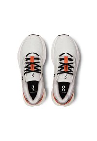 Witte sportschoenen met een bovenwerk van mesh, zwarte veters, oranje accenten en een gevoerde zool. "On" logo zichtbaar op de hiel en de tong.