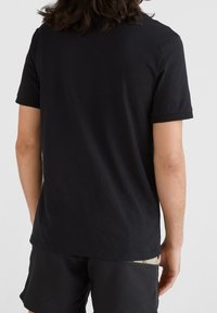 T-shirt noire à manches courtes, en tissu doux, avec un col rond et un ourlet droit. La vue arrière montre une texture lisse et une simplicité.