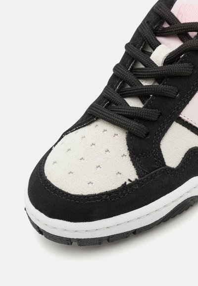 Schwarze Wildledersneaker mit pinkem Akzent, cremefarbenem Paneel mit Perforationen und schwarzen Schnürsenkeln. Weiße Zwischensohle mit strukturiertem schwarzen Außensohlen.