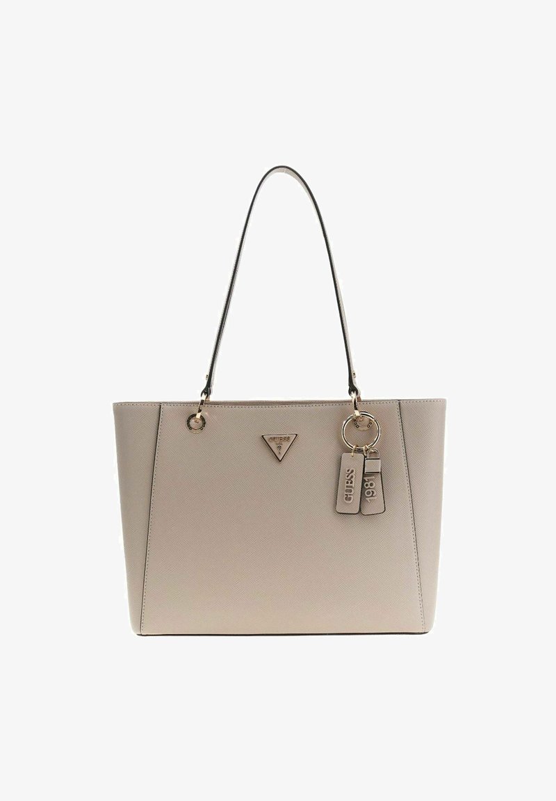 Sac cabas beige Guess avec une seule bandoulière noire, ferrures dorées, logo triangulaire et porte-clés avec les inscriptions "Guess" et "1981".