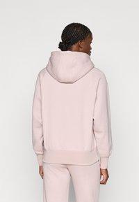 Hoodie rose clair en tissu doux, doté d'une grande capuche, de poignets et d'une taille côtelés, et d'une coupe décontractée.