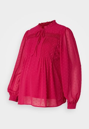 Fuchsia blouse van doorschijnende, gestructureerde stof met plooien en een striknek. Lange, opbollende mouwen en een gekartelde kraag.