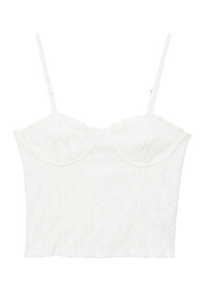 Crop top en dentelle blanche avec bretelles spaghetti ajustables et bonnets à armatures avec un motif floral ajouré.