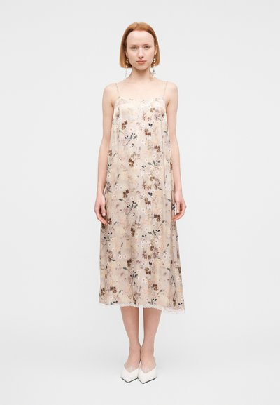Robe nuisette beige imprimée de fleurs avec fines bretelles spaghetti, longueur mi-mollet, bordure en dentelle, tissu léger et fluide.