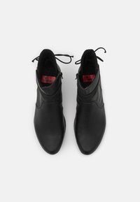 Bottines noires en cuir avec une finition lisse et brillante, présentant une fermeture éclair et des lacets réglables, avec un intérieur doublé en douceur.