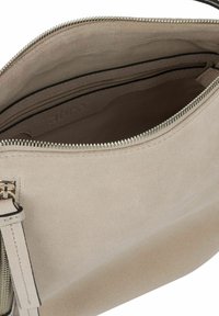 Beige suède handtas met een ritsluiting, met een zachte textuur en minimalistisch ontwerp. Interne compartimenten zichtbaar bij de opening.