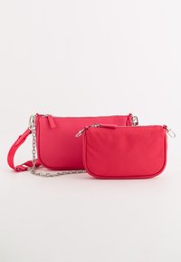 To pink nylon tasker, en større med en kædrem og lynlås, den anden mindre og lynlåset med en rund form.