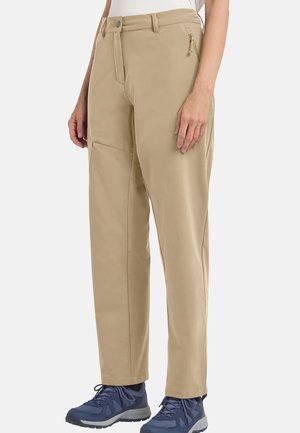 Beige Hose mit geradem Bein und Reißverschlusstaschen an den Seiten, getragen mit blauen Wanderschuhen und weißem Oberteil, von der Taille abwärts gezeigt.