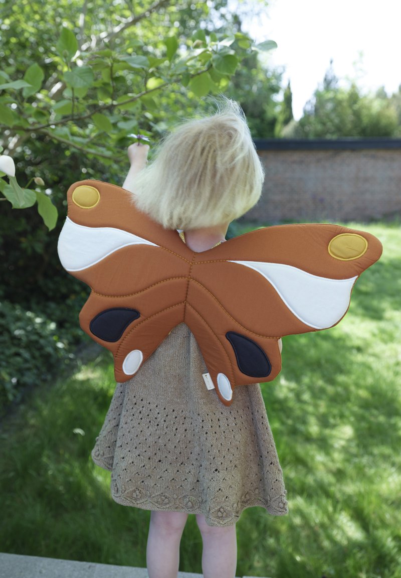 Alas de mariposa marrones y blancas hechas de tela, con detalles en negro y amarillo, llevadas en la espalda de un niño que está de espaldas al espectador.