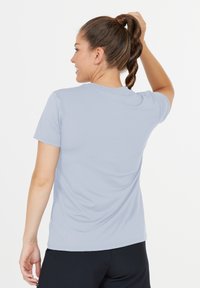 Ljusblå kortärmad träningsskjorta med slät textur och klassisk rund halsringning, bärs med mörka träningsbyxor.